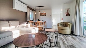 A modern living room with a sofa, two coffee tables, a dining area with a table and chairs, and a large window with curtains. - Beautiful home in Giethoorn with WiFi (Giethoorn)