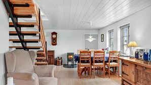 A cozy living room with a fireplace, wooden furniture, and a staircase. - 1 bedroom beautiful home in Roslev (Roslev)