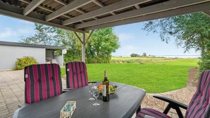 An outdoor patio with a table set for two, featuring striped chairs, a bottle of wine, and a bowl of fruit. - 1 bedroom beautiful home in Roslev (Roslev)