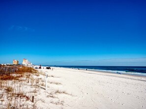 Een strand met een heldere lucht, een zandstrand en gebouwen op de achtergrond.