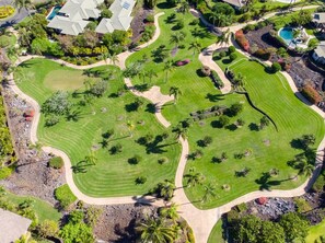 Une vue aérienne d’un parcours de golf avec plusieurs greens, des bunkers de sable et une variété d’arbres.