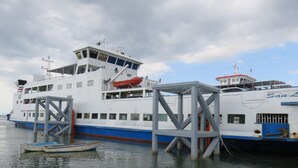 Un grand ferry était amarré à un quai, avec un plus petit bateau en premier plan.