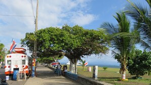 Une rue où est garé un autobus, un trottoir et une vue sur l’océan.