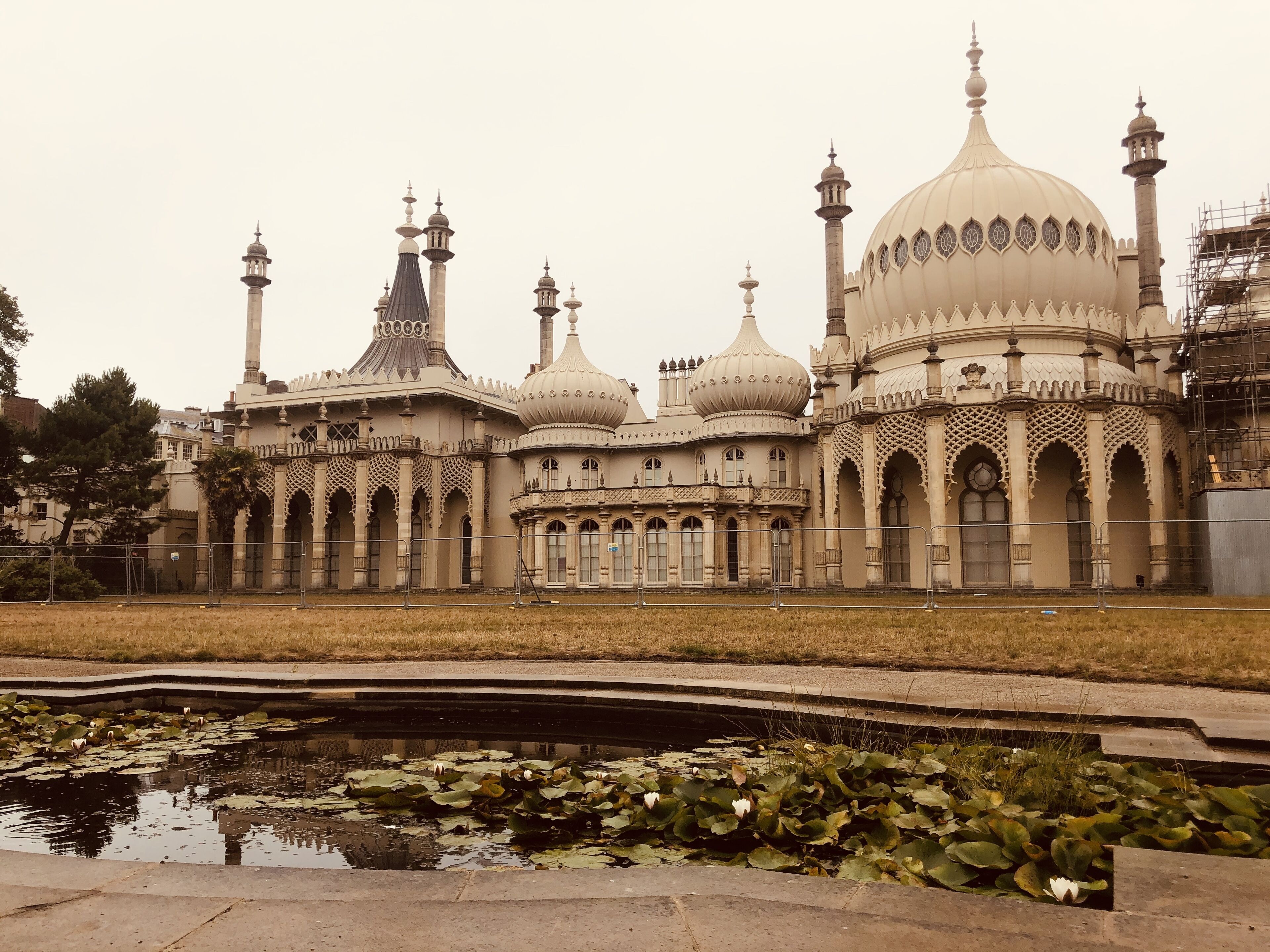 A large, ornate building with multiple domes and minarets, surrounded by a pond with lily pads.