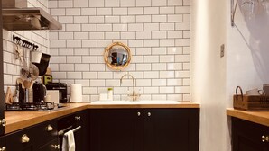 Una cocina compacta con salpicadero de azulejos blancos, armarios negros y un suelo con estampado de estrellas.