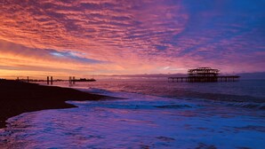 Una playa con un muelle que se adentra en el agua durante el atardecer.