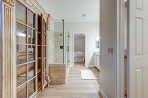 Un couloir avec une douche en verre, un meuble en bois et une porte blanche.