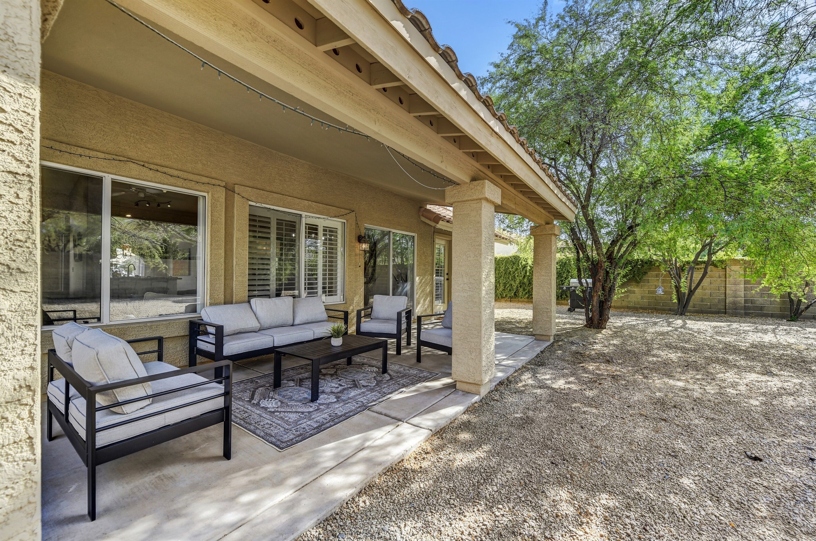 A covered patio area with outdoor furniture, including a sofa and chairs, and a coffee table.