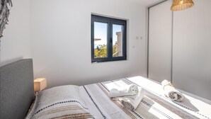 Una camera da letto con un letto, una finestra, una lampada a sospensione e una porta.