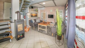 Una sala de estar acogedora con chimenea, un sofá, una mesa de comedor y una escalera que sube a un nivel superior.