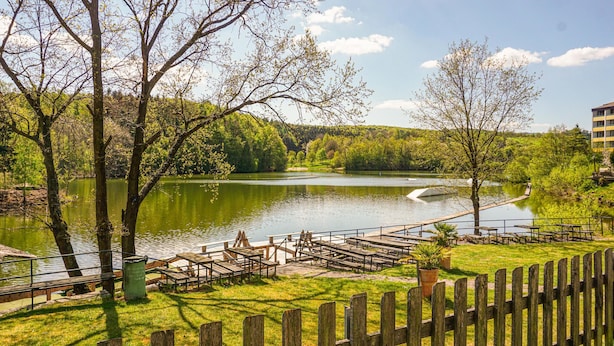 Un parque junto al lago con mesas de picnic y una terraza de madera.