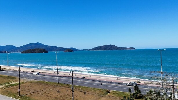 Una carretera costera con una playa y montañas al fondo.