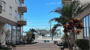 Un patio con camino de adoquines, bancos y palmeras.