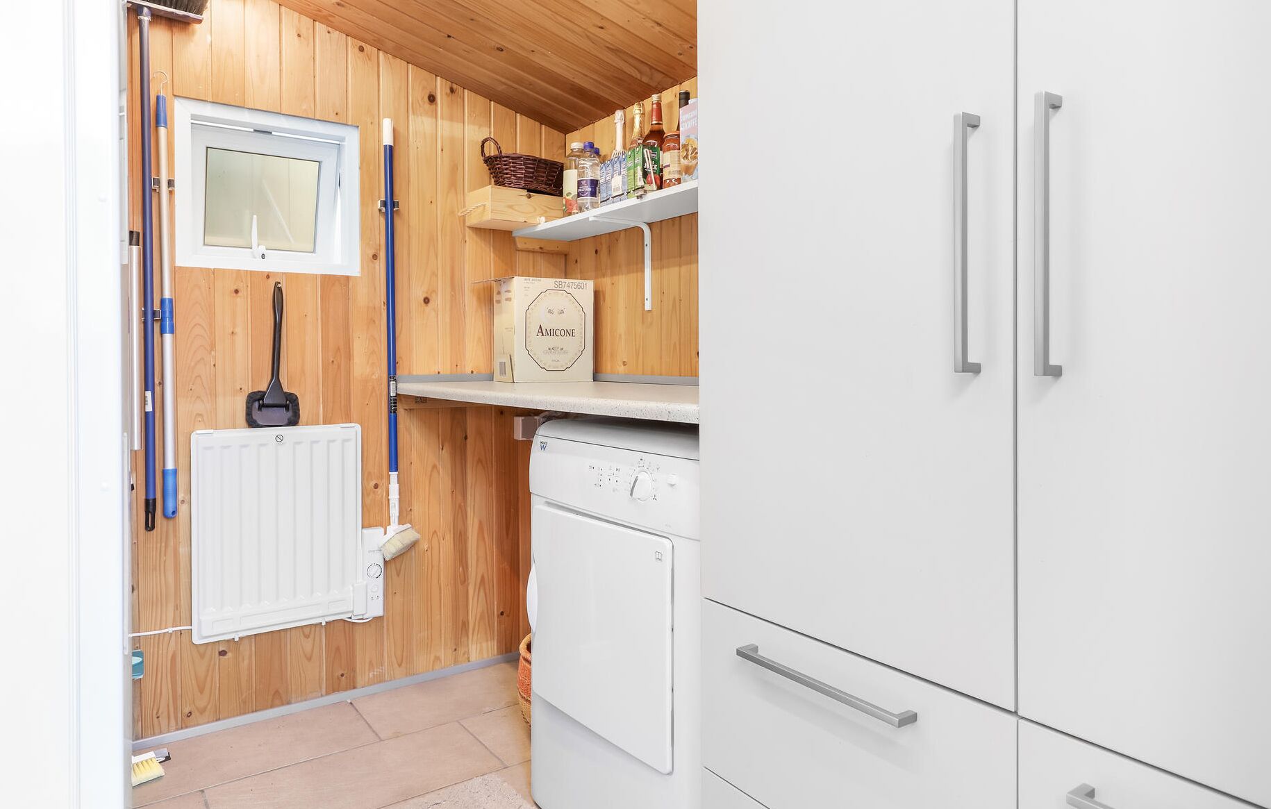 A compact kitchen with wooden walls, a white refrigerator, a stove, and a window.