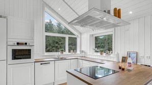 A modern kitchen with white cabinetry, a built-in oven, a large window, and a wooden countertop. - Cozy home in Nexø with kitchen (Nexø)