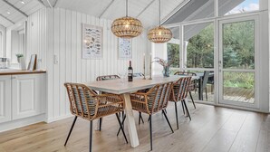 A dining area with a wooden table, wicker chairs, and two hanging wicker chandeliers. - Cozy home in Nexø with kitchen (Nexø)
