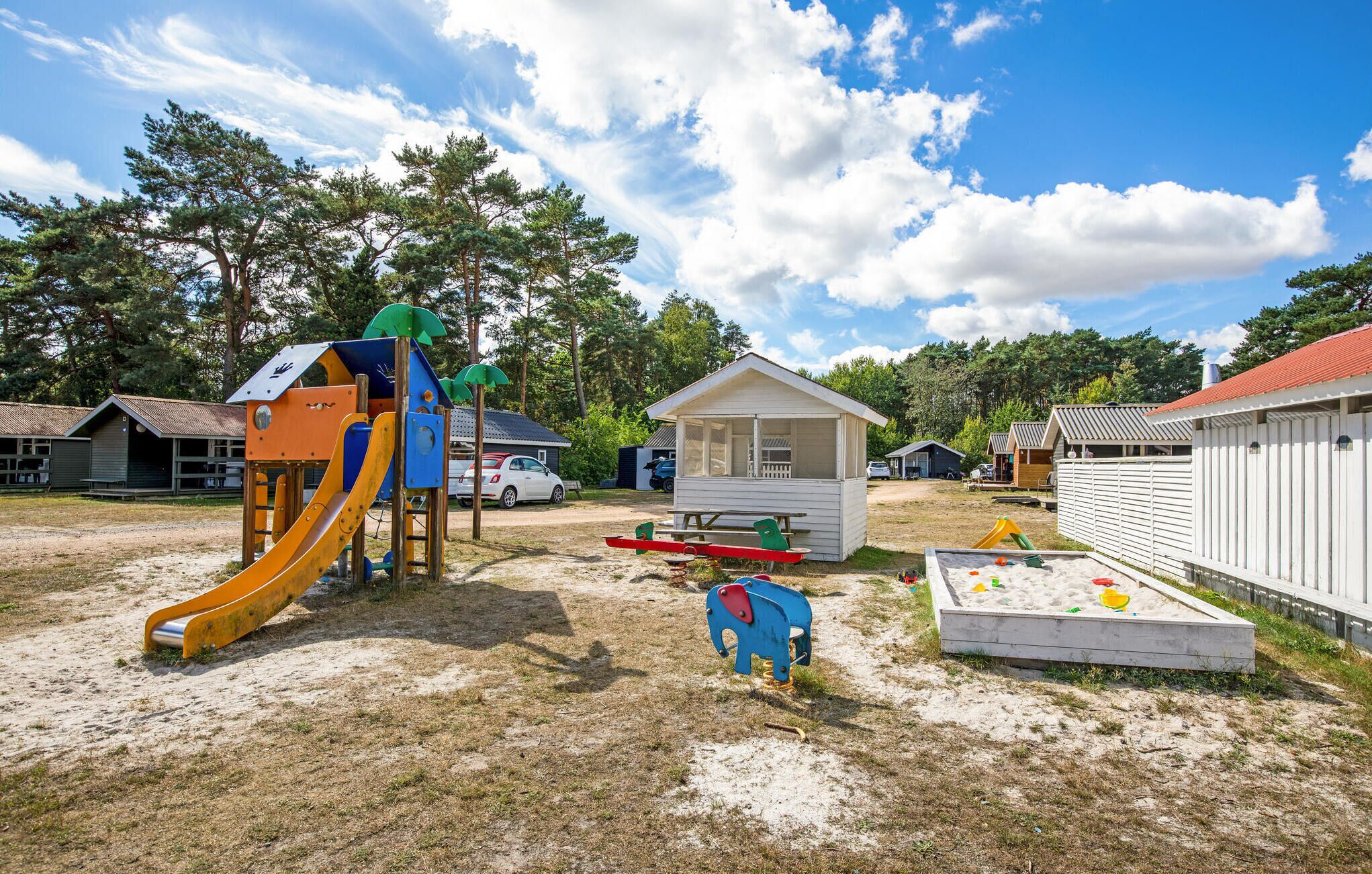 A playground with a slide, swings, and a sandpit.