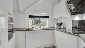 Une cuisine moderne avec des meubles blancs, une fenêtre offrant une belle vue et un plan de travail noir.