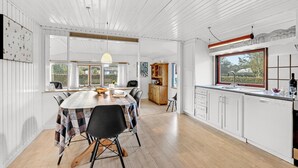 A spacious kitchen with a wooden table, modern chairs, and a large window.