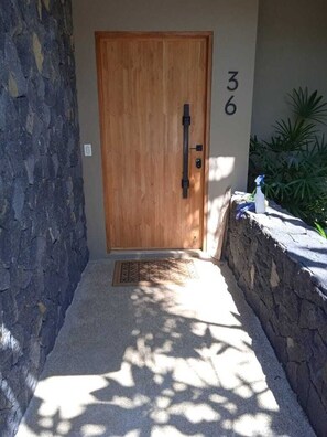 A wooden door with a number '36' on the wall beside it, a stone wall to the left, and a small step leading to the door.