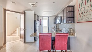 Una cocina moderna con una isla central, taburetes rojos y un póster de chile en la pared.
