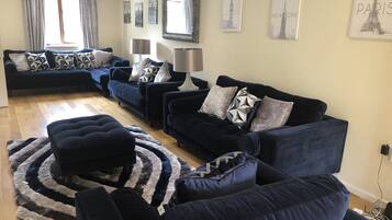 A living room with two dark blue sofas, a patterned rug, and cityscape wall art.