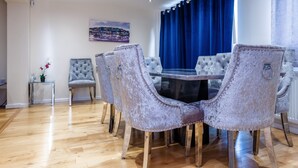 A dining area with a round table and six upholstered chairs with metal legs.