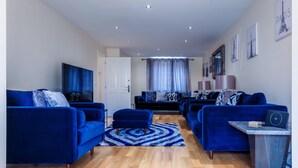 A modern living room with blue sofas, a coffee table, and a TV.