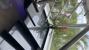Eine Glastrennwand mit Metallgeländern, ein Blumentopf und Blick ins Grüne.