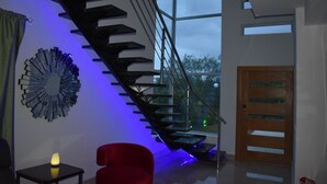 Ein modernes Interieur mit Treppe, einem roten Sessel, einem Wandbild und einer Holztür.