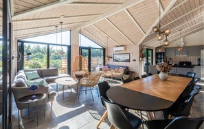 A spacious living area with a large wooden dining table, comfortable seating, and a view of the outdoors. - Cozy home in Ejstrupholm (Ejstrupholm)
