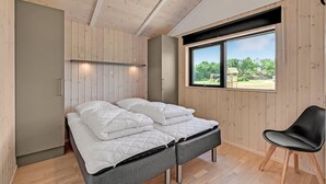 A bedroom with a bed, a chair, and a window with a view of greenery. - Cozy home in Ejstrupholm (Ejstrupholm)