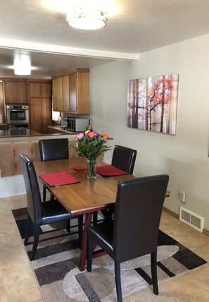 Enjoy meals in this cozy dining area with a wooden table and comfortable seating.
