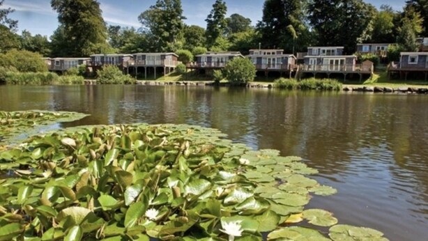 A lake with lily pads and a row of waterfront houses. - Holiday Cabin Sleeps 5 Caernarfon, Snowdonia (Caernarfon)