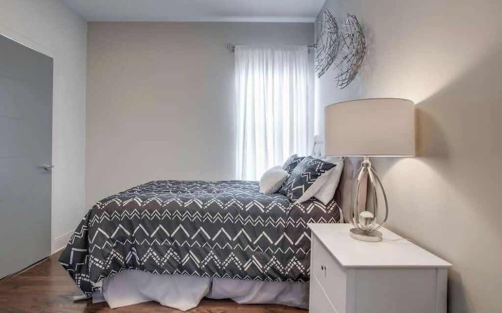 A bedroom with a bed, a bedside lamp, and a window with curtains.