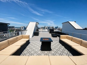 Terraza en la azotea con vistas a la ciudad, que cuenta con un área de estar con sofás y una mesa, y un suelo con diseño.