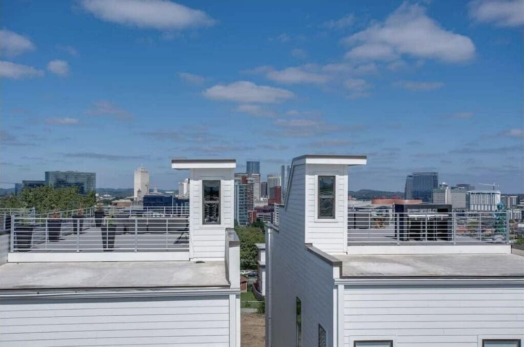Ein Dach mit weißen Gebäuden, einem klaren Himmel und einer Stadtlandschaft im Hintergrund.
