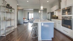 A modern kitchen with a central island, stainless steel appliances, and a bar stool. - Stunning Nashville Retreat - Near Broadway (Nashville)