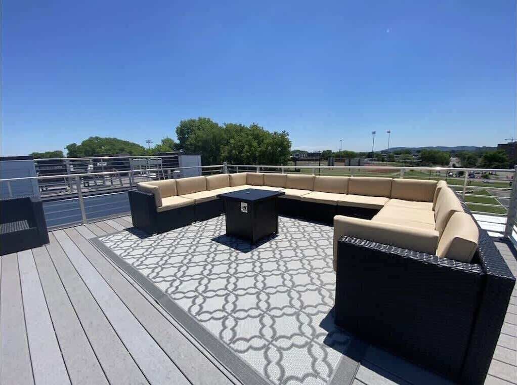An outdoor deck with a sectional sofa and a small table, surrounded by a patterned floor.
