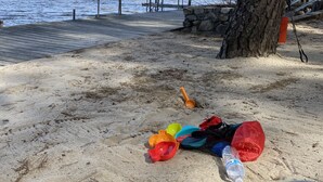 En sandstrand med en træbro, der strækker sig ud i et roligt vand.