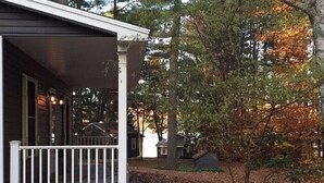 Et hus med en veranda og et mindre udhus i et skovområde.