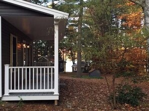 Situated in a secluded natural setting, this single-story home features a charming covered porch with a white railing.