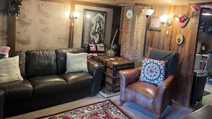 A cozy living room with a brown leather sofa, a brown leather armchair, and a patterned rug.