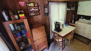A compact kitchen with wooden cabinets, a coffee maker, and a dining table.