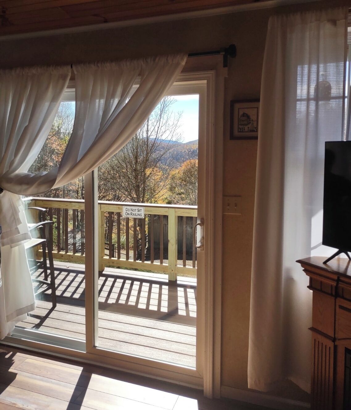 Une pièce dotée d’une porte-fenêtre coulissante donnant sur un balcon où est affiché un panneau indiquant « Il est interdit de s’asseoir sur les balustrades ».
