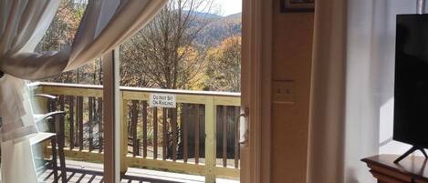 A room with a sliding glass door leading to a balcony with a 'Do Not Sit on Railings' sign.