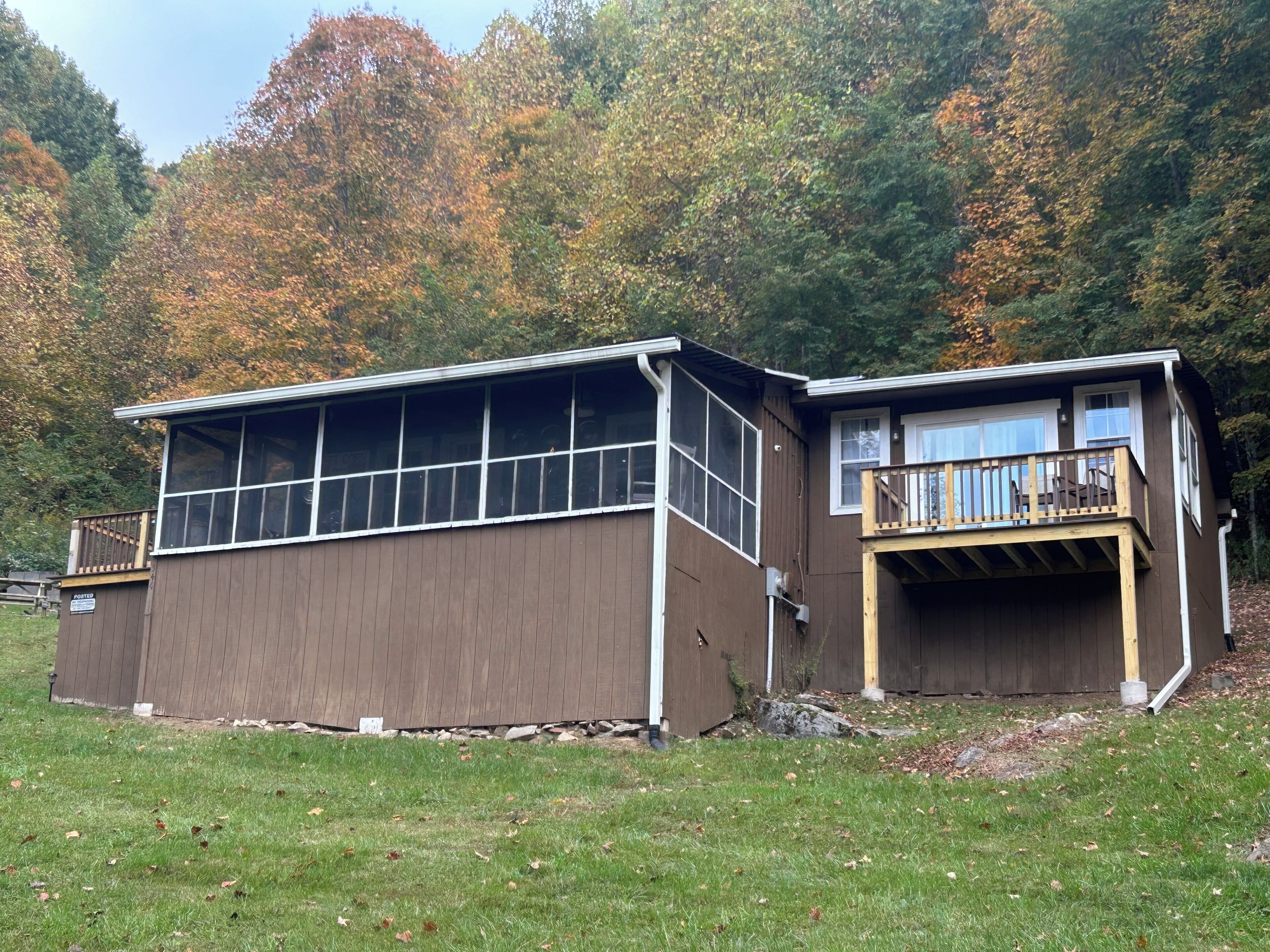 Eine zweistöckige Holzhütte mit einer großen Veranda und einem Deck.