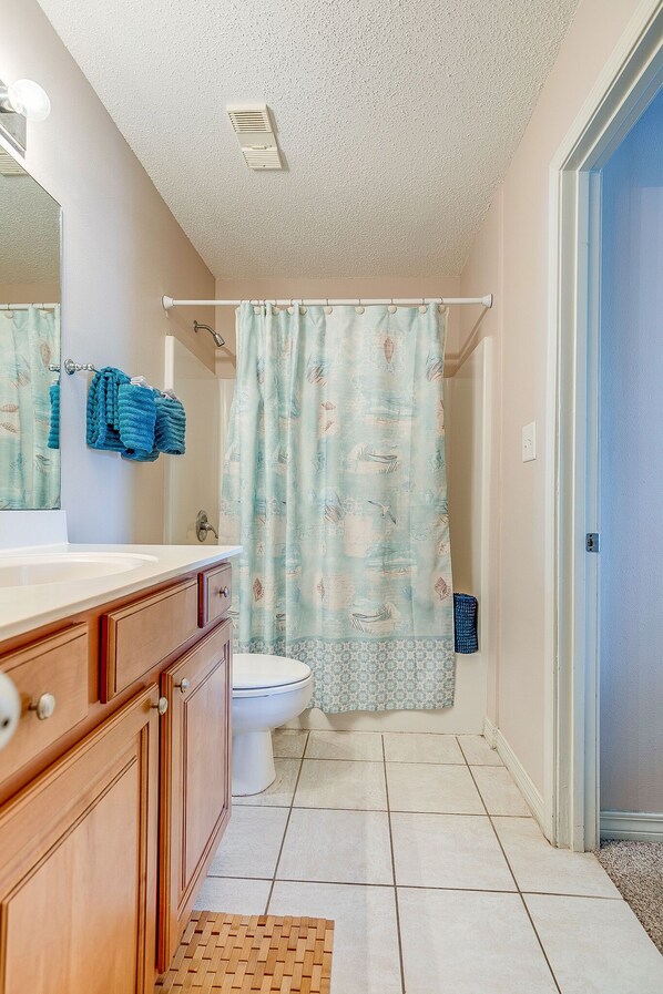 A bathroom with a wooden vanity, a white sink, a toilet, and a shower curtain. - Ground Floor Crystal Beach Condo, Steps to the Beach, Next to Pool and Hot Tub (Destin)