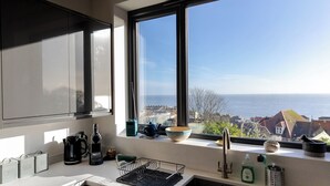 A kitchen with a view of the sea, a sink, and a window with a view. - Seagrass - Dog Friendly-Hot Tub-Sea Views-Sleeps 4 (Ventnor)