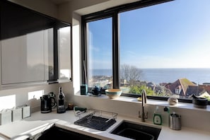 A kitchen with a view of the sea, a sink, and a window with a view.